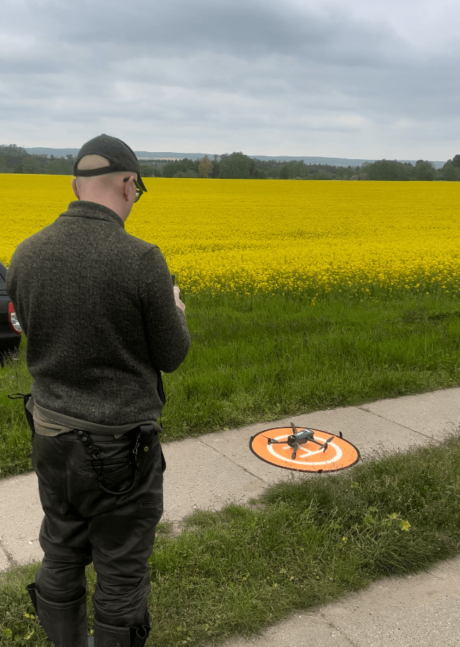 Person startet Drohne auf Landefeld im Freien.