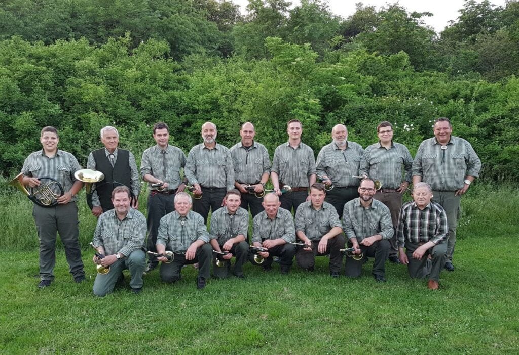 Blaskapelle spielt in traditioneller Kleidung bei Veranstaltung.